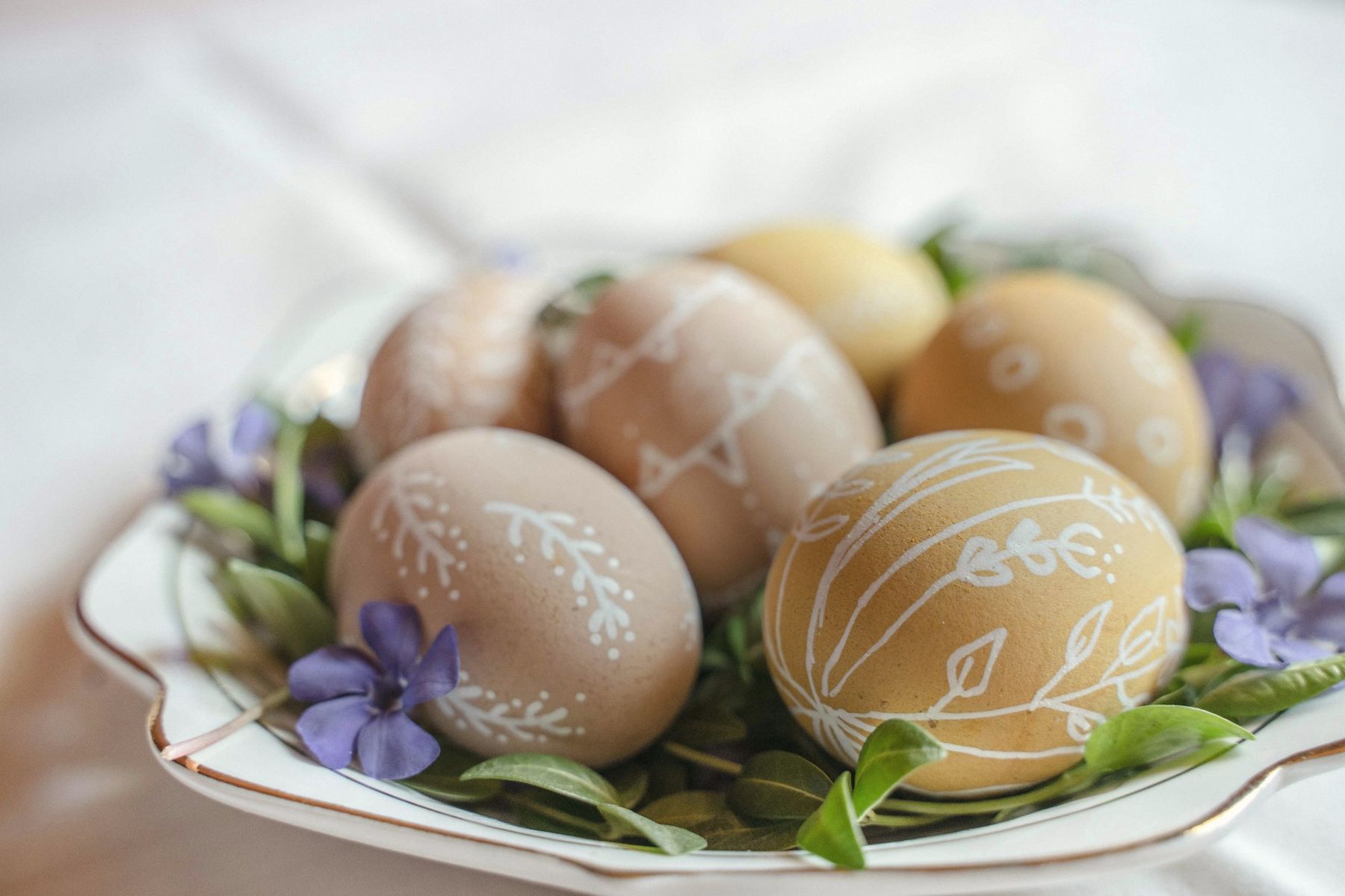 Hand-painted eggs on a plate with violets