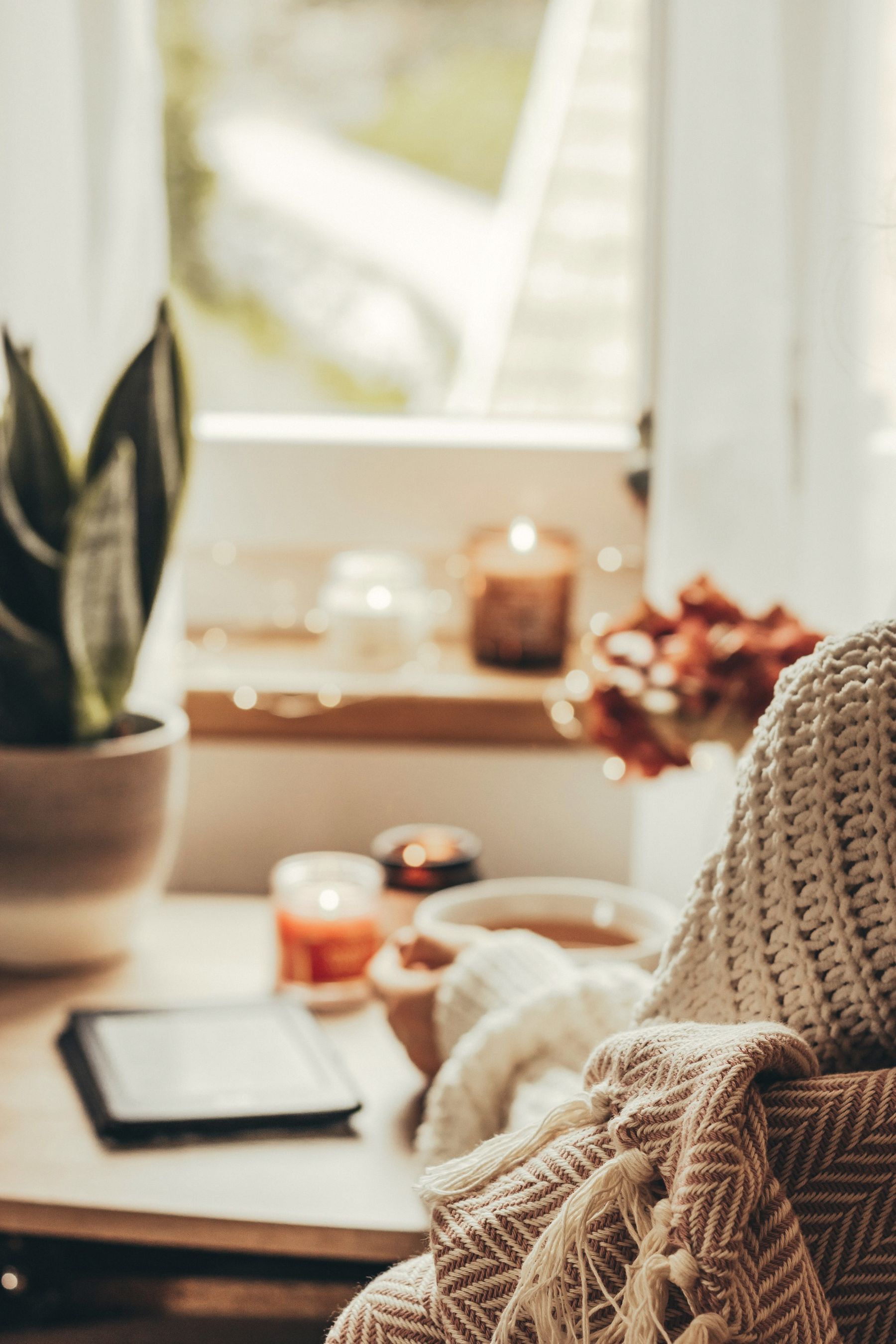 A quiet winter reading corner with a knit throw, candle and tea
