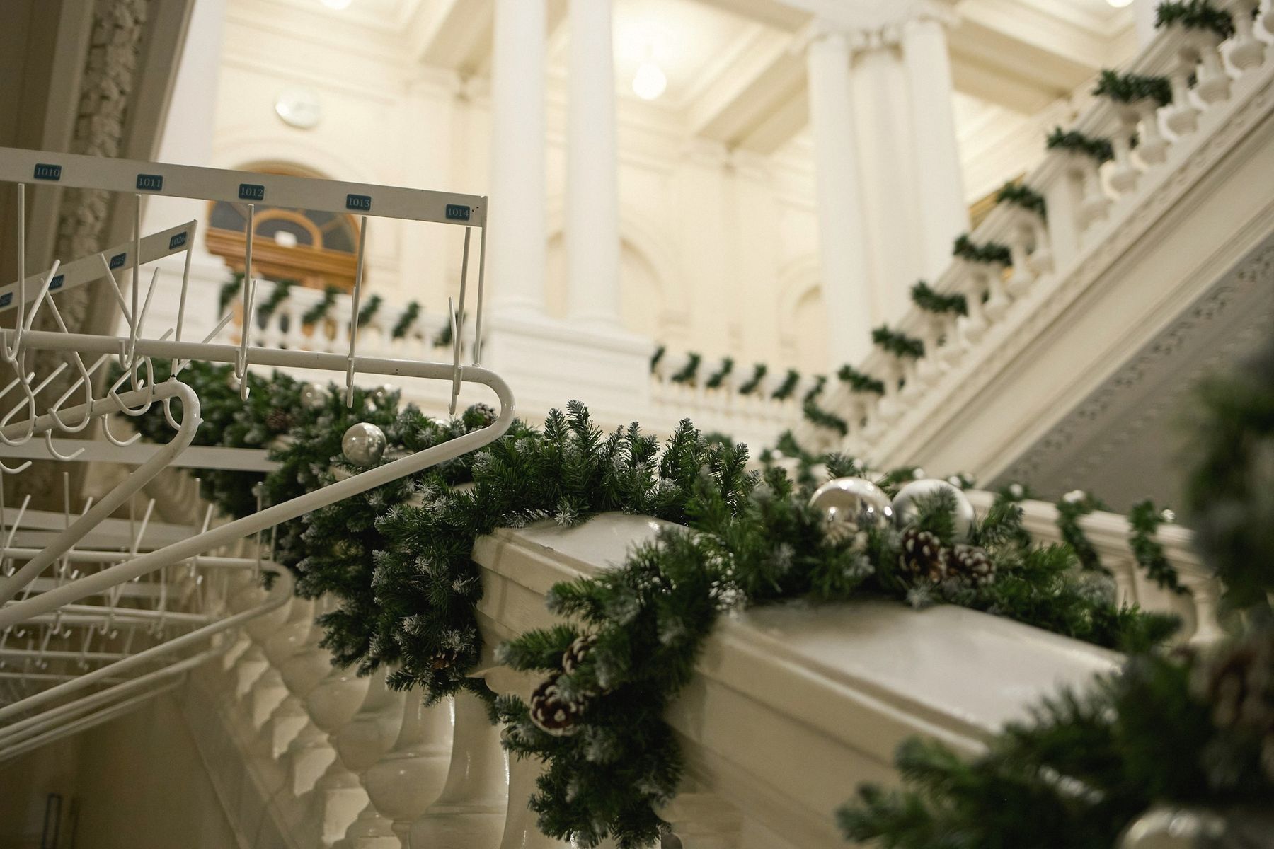 A white staircase banister wrapped in evergreen garland